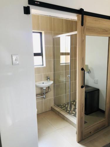 a bathroom with a glass shower and a sink at Tranquility Guesthouse in Standerton