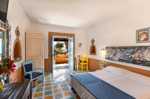 Habitación de hotel con cama, mesa y sillas en Hotel Mamma Santina, en Santa Marina Salina