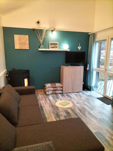 un salon avec un canapé et une télévision à écran plat dans l'établissement Au bord du lac, à Royère-de-Vassivière