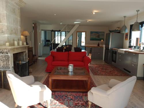 a living room with a red couch and two white chairs at GITE LE SERPOLET BORD DE MER in Saint Martin de Brehal