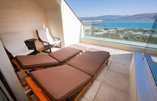 a room with two beds and a view of the ocean at Hotel Boutique O Náutico Laxe in Laxe