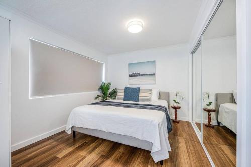 Dormitorio blanco con cama y ventana grande en Lovely 2bd Unit, Patio and views. Best weekly rate, en Alexandra Headland