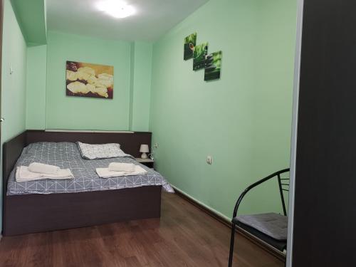 um pequeno quarto com uma cama e uma cadeira em Двустаен апартамент в центъра на гр. Бургас em Burgas