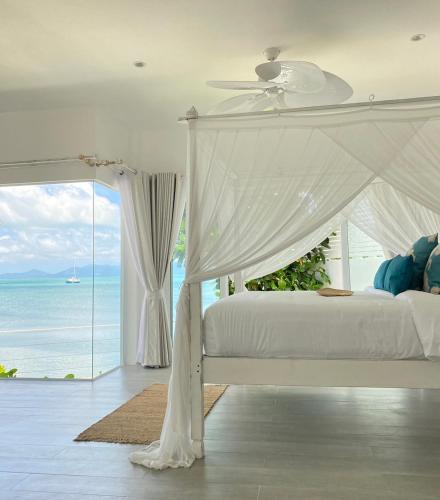 a bedroom with a canopy bed with a view of the ocean at Tembo Beach Club & Resort in Bangrak Beach