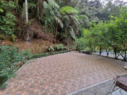 a brick walkway in a park with trees at Highlanders Garden Guesthouse at Arundina Cameron Highlands in Cameron Highlands