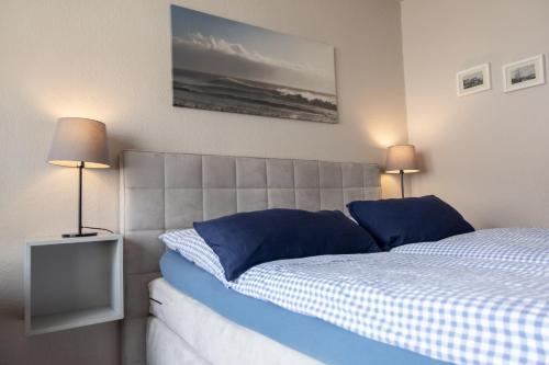 a bedroom with a bed with blue pillows and two lamps at Heimathafen in Büsum