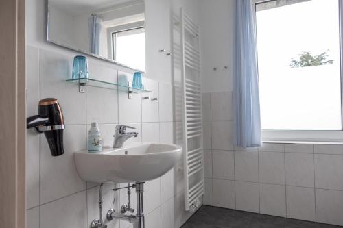 a white bathroom with a sink and a window at Heimathafen in Büsum