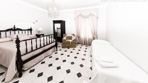 a white bedroom with two beds and a chair at Cal Xamora in Biosca