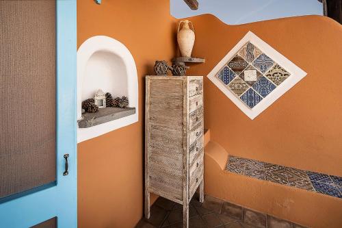 a room with an orange wall with a shelf and a window at Hotel Mamma Santina in Santa Marina Salina