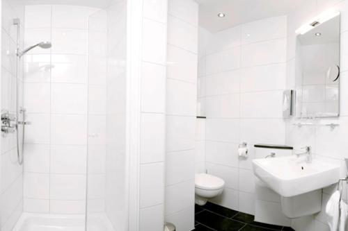 a white bathroom with a sink and a toilet at Hotel Restaurant Rüwe in Löningen