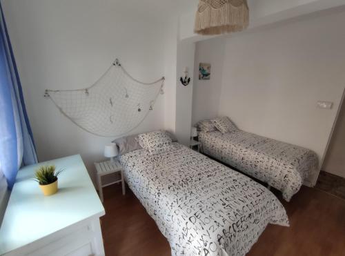 a bedroom with two beds and a table at Apt VILLA CUDILLERO in Cudillero