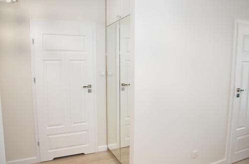 a closet with white doors and a mirror at Apartament Luna Baltic Marina Residence in Kołobrzeg