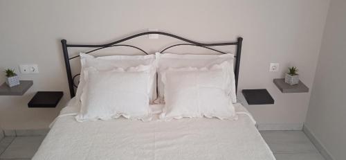 a bed with white sheets and pillows at Kate's family house in Pylos