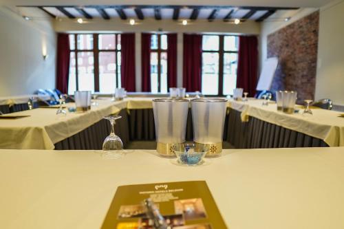 a table in a restaurant with white tables and glasses at Ghent River Hotel in Ghent