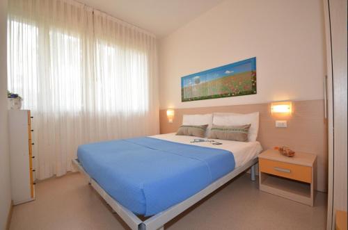 sypialnia z dużym łóżkiem i niebieskim kocem w obiekcie Green Holiday Village with Pool w Bibione