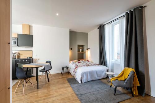 une chambre avec un lit, une table et des chaises dans l'établissement Maloca' Joffre, à La Roche-sur-Yon