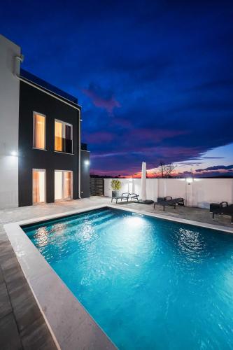 a swimming pool in front of a house at night at D-Palace Apartments-Olive tree in Donji Zemunik