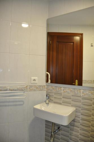 Baño blanco con lavabo y espejo en Alojamiento Santa Maria II, en Milladoiro