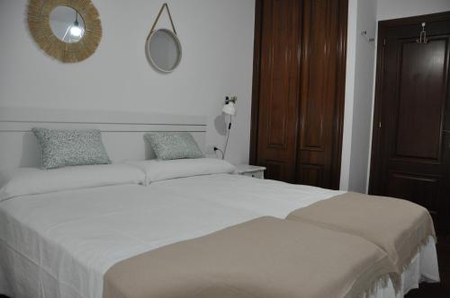 1 dormitorio con 1 cama blanca grande y espejo en Alojamiento Santa Maria II, en Milladoiro