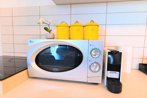 a microwave with yellow cups on top of it at YalaRent Migdalor Apartments with Sea Views Tiberias in Tiberias