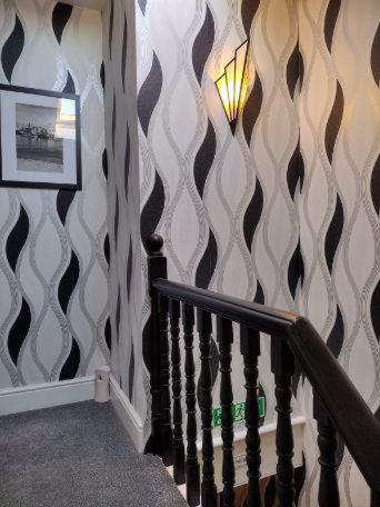 a hallway with a staircase with a wall with black and white wallpaper at Seaview B&B in Harwich