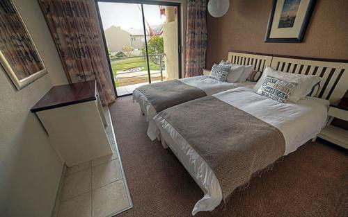 a bedroom with a large bed and a mirror at Beach Lodge in Swakopmund