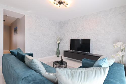 a living room with a blue couch and a tv at D-Palace Apartments-Olive tree in Donji Zemunik