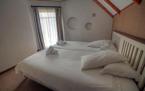 a large white bed in a bedroom with a window at Beach Lodge in Swakopmund