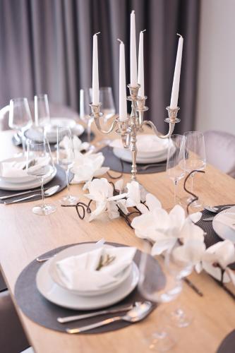 a wooden table with white plates and candles on it at D-Palace Apartments-Olive tree in Donji Zemunik