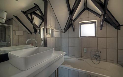 a bathroom with a white sink and a tub at Beach Lodge in Swakopmund