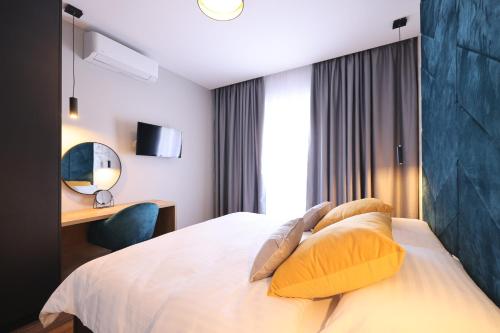 a hotel room with a bed with yellow pillows at D-Palace Apartments-Olive tree in Donji Zemunik