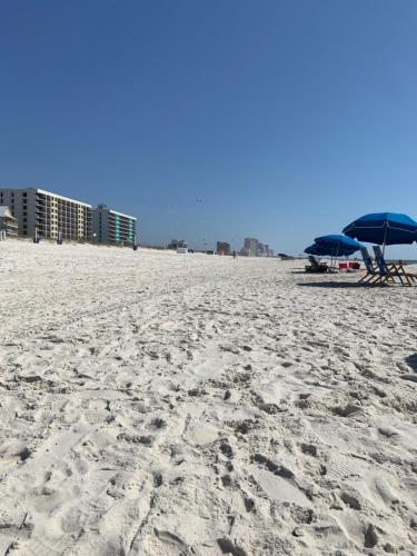 two blue umbrellas and chairs on a sandy beach at 2-Bedroom Condo on Gulf Shores Beach w/Pool in Gulf Shores