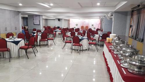 a dining room with tables and red chairs and tablesktop at Hotel Opal in Kolhapur