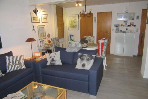 sala de estar con sofá azul y 2 almohadas para perros en Luett Hues, en Scharbeutz
