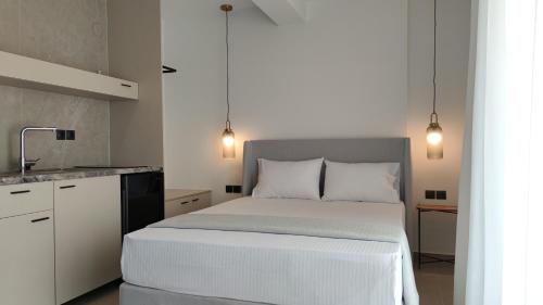 a bedroom with a white bed and a kitchen at Onar in Sarti in Sarti