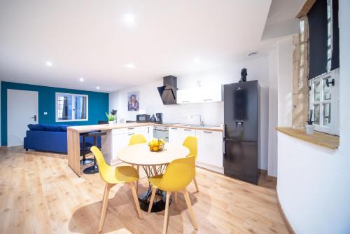 uma cozinha e sala de jantar com mesa e cadeiras amarelas em Appartement POP au coeur du centre ville em Mâcon