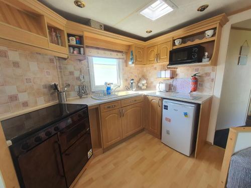 a kitchen with wooden cabinets and a sink and a dishwasher at The Topaz Caravan HF12 in Ingoldmells