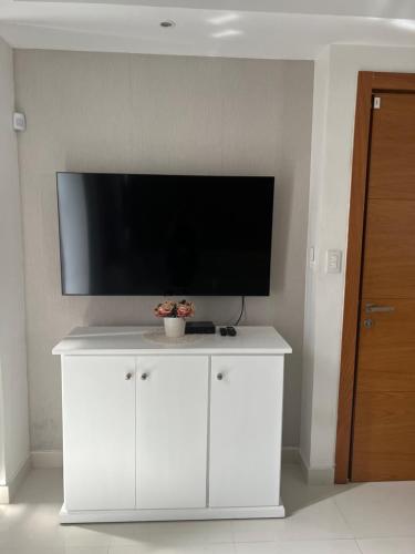 a white cabinet with a flat screen tv on a wall at AMG Suites Apartment in Santo Domingo