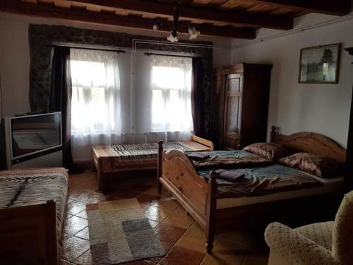 a bedroom with two beds and a tv and a window at Bableves Vendégház in Felsőtold