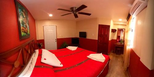 a bedroom with a red bed with a ceiling fan at Venus Hotel in San Ignacio