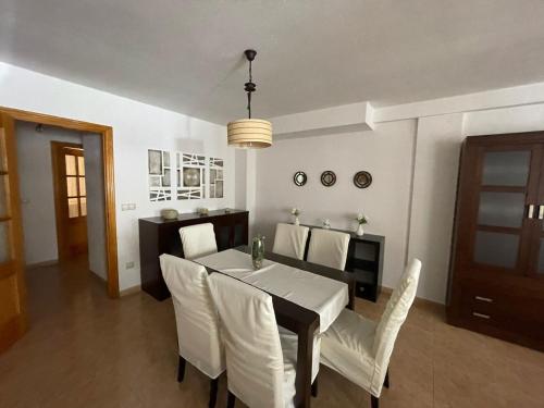 a dining room with a table and white chairs at Casa Moraira in Águilas