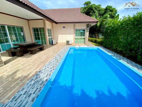 a blue swimming pool in front of a house at Sand-D House Pool Villa A13 at Rock Garden Beach Resort Rayong in Mae Pim