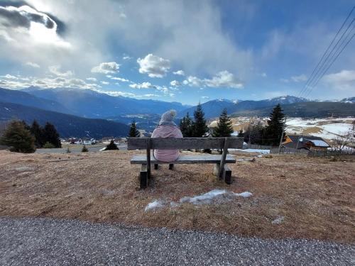 a person sitting on a bench looking at the mountains at Pitznerhof in Maranza