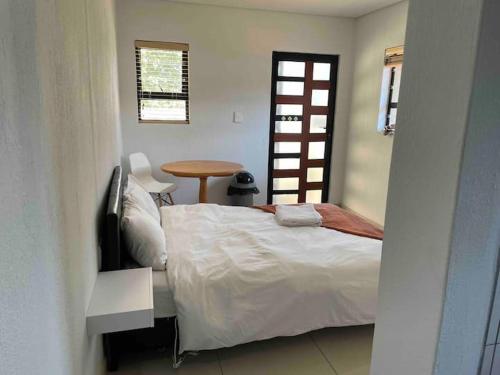 um quarto com uma cama, uma mesa e uma janela em Private and cozy em Sandton