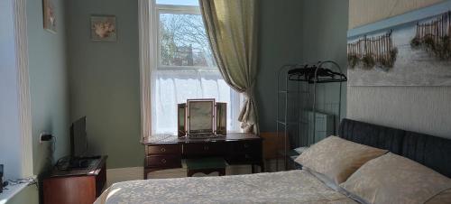 1 dormitorio con 1 cama y ventana con reloj sobre una mesa en Fishtail House - Stylish Apartments minutes from the sea, en Hornsea