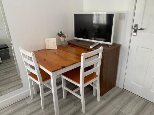 a wooden desk with a television and two chairs at Dream Ensuite Rooms in Birmingham