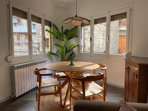 a dining room with a table and chairs and windows at CHECK-IN CASAS Casa Aurora in Benasque
