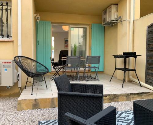 a patio with chairs and a table and a piano at Maison T4 -Jardin+ Parking+ Clim -Proche Remparts in Aigues-Mortes