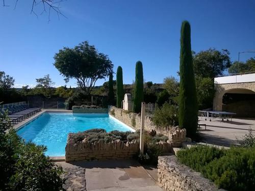 a swimming pool in a yard with cypress trees at Bastidon avec piscine Gordes Lubéron in Gordes