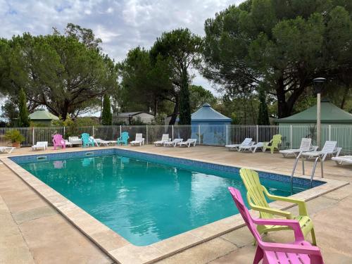 a swimming pool with colorful chairs and tables at Budget Glamping Safaritent - Mas de Mourgues in Vauvert